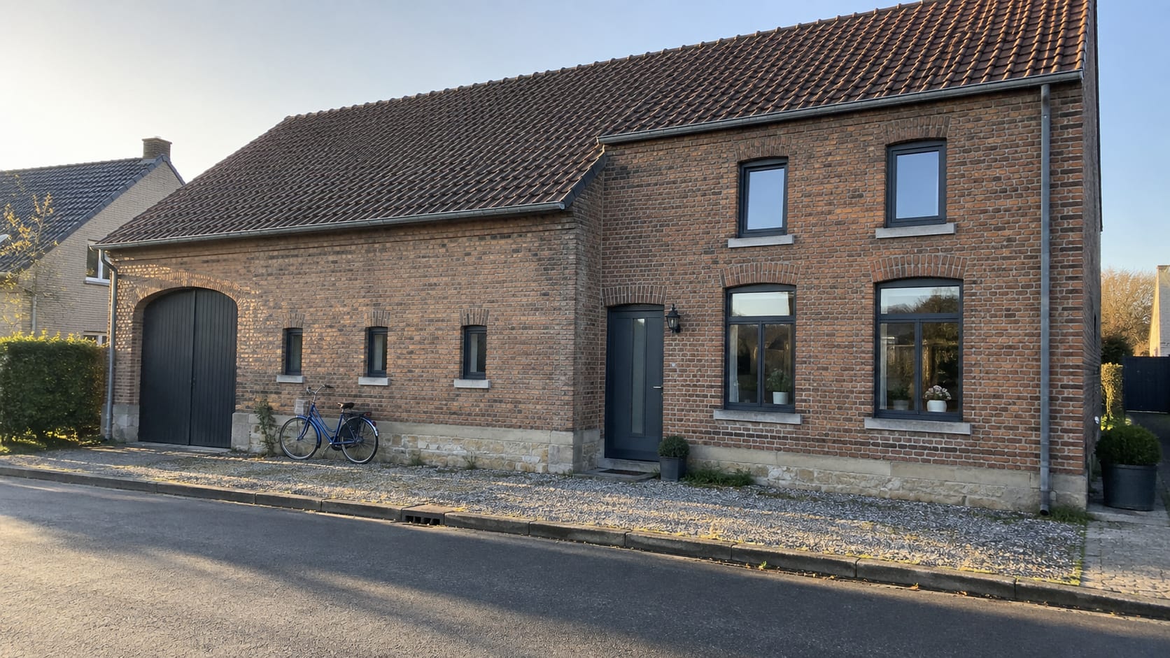 Straatgevel van een oude bakstenen boerderij in een dorp, met overal nieuwe kozijnen in één kleur