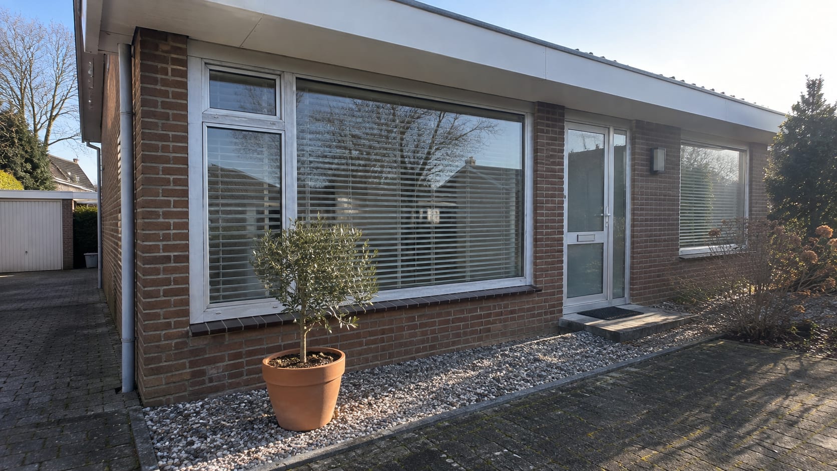 Voor: dof geworden blank aluminium kozijnen in de gevel van een bungalow