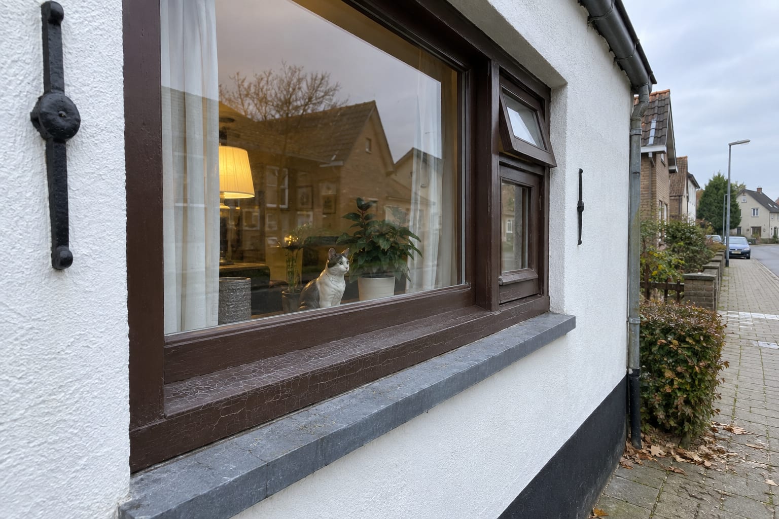Voor: een bruin houten kozijn met doffe, gebarsten verf op de onderdorpel