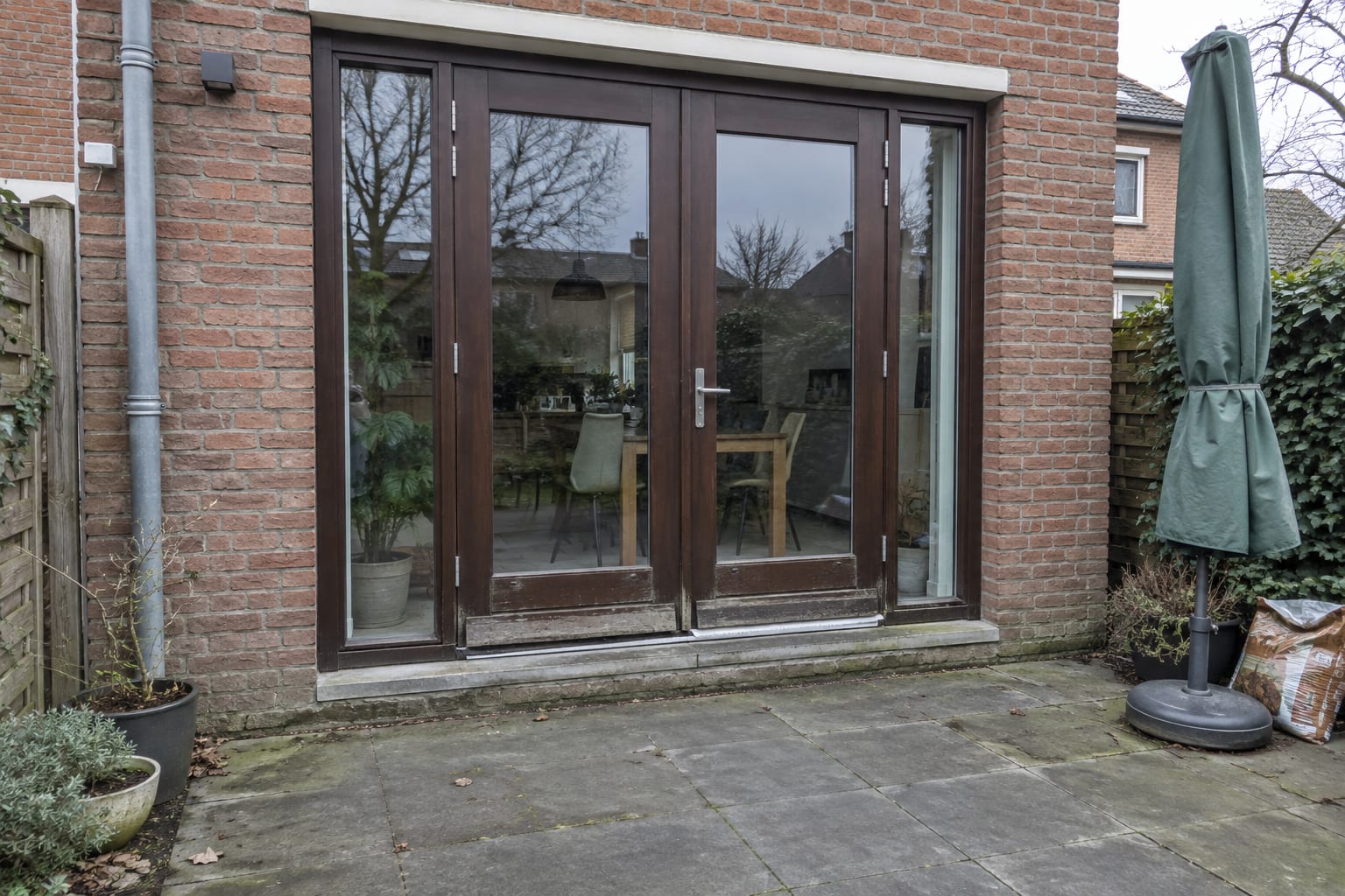Voor: bruine houten openslaande tuindeuren met een hoge drempel